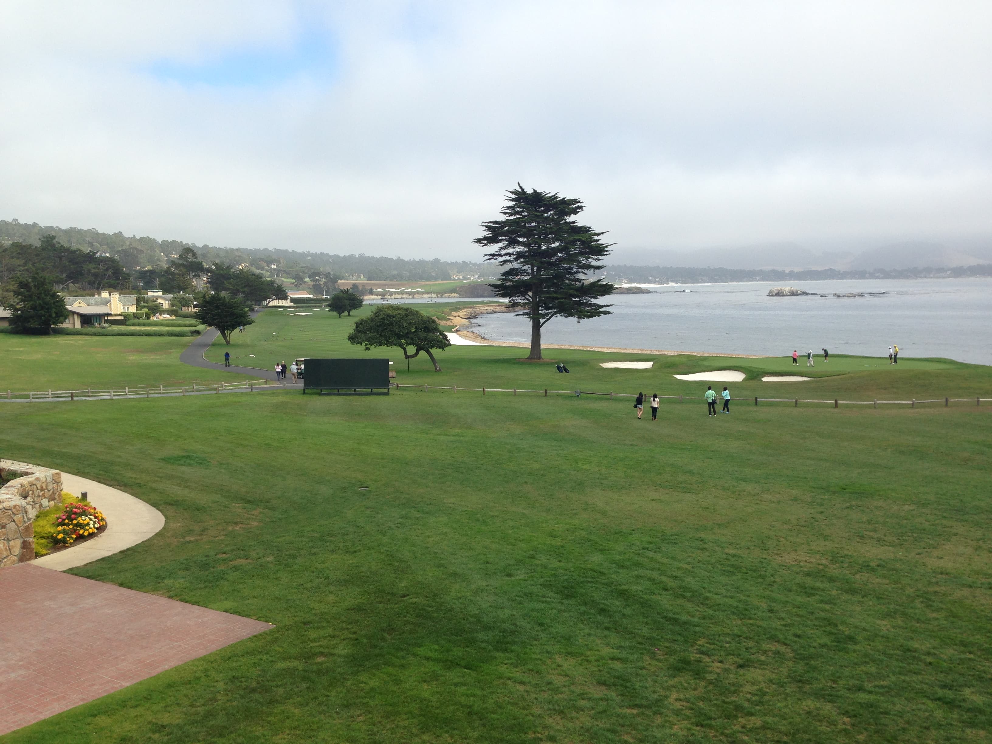 The 18th hole green at Pebble Beach Golf Links beside the Pacific coastline.